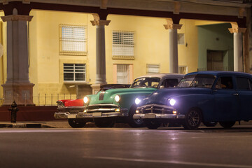 Obraz na płótnie Canvas Amazing old american car on streets of Havana with colourful buildings in background during the night. Havana, Cuba.