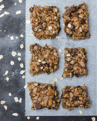 peanut butter chocolate chip granola bars with oats on white parchment paper with neutral background
