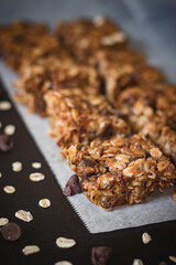 peanut butter chocolate chip granola bars with oats on white parchment paper with neutral...