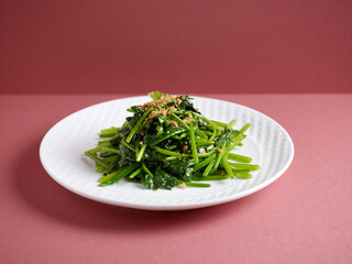 Stir-Fried Spinach with Garlic with chopsticks served in a dish isolated on mat side view on grey background