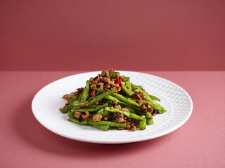 Stir-fried French Beans with Minced Pork and Preserved Olive Vegetables with chopsticks served in a dish isolated on mat side view on grey background