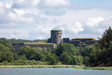 Fototapeta premium View of Bohus fortress and water inlet. Lush summer trees and reeds, no visible people