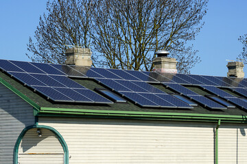 Many photovoltaic solar panels mounted on the old large wooden house roof