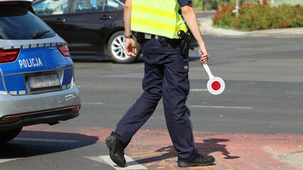 Policjant ruchu drogowego z lizakiem do zatrzymywania pojazdów w mieście kontroluje ruch na zabezpieczeniu. 