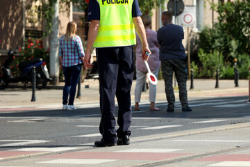 Policjant ruchu drogowego z lizakiem do zatrzymywania pojazdów w mieście kontroluje ruch na zabezpieczeniu.  - obrazy, fototapety, plakaty