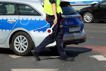 Policjant ruchu drogowego z lizakiem do zatrzymywania pojazdów w mieście kontroluje ruch na zabezpieczeniu.  - obrazy, fototapety, plakaty