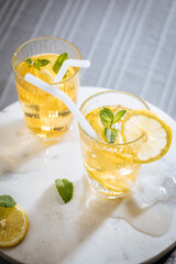 Ice tea with lemon and mint leaves. Served with ice on marble background. Summer refreshing...