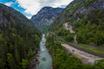 Fototapeta na wymiar Drone aerial view of wild river Enns in cloudy weather in Gesause National Park near town of Admont in centre Austria. Visible long valley, clear blue water, road and railway.