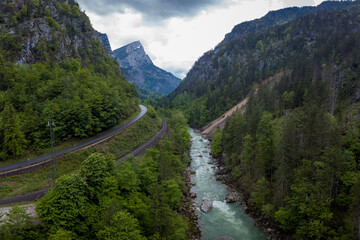 Drone aerial view of wild river Enns in cloudy weather in Gesause National Park near town of Admont in centre Austria. Visible long valley, clear blue water, road and railway.