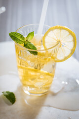 Ice tea with lemon and mint leaves. Served with ice on marble background. Summer refreshing cocktail drink