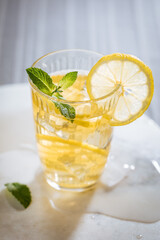 Ice tea with lemon and mint leaves. Served with ice on marble background. Summer refreshing cocktail drink