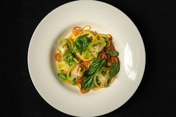 vegan dish with spaghetti, cherry tomatoes, green tomatoes and basil