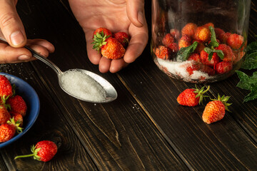 Before preparing a sweet compote of fresh strawberries and mint, you must add sugar. Close-up of chef hands while preparing a drink