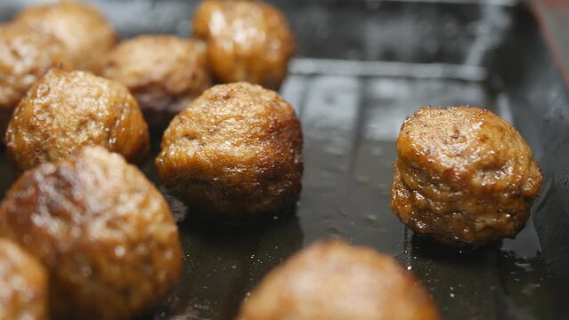 fried round meatballs on a metal pan dolly shot, close-up