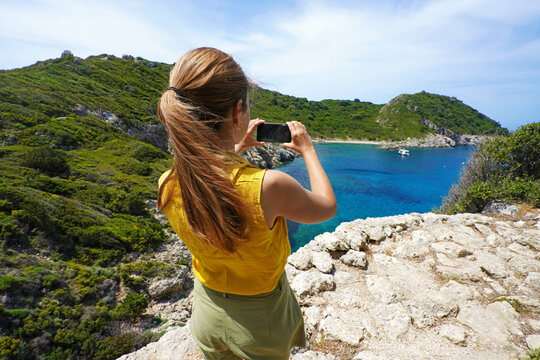 Young hiker explorer girl taking picture with smartphone of natural tropical panoramic view. Wide angle. Windy day.