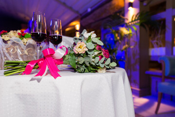 Centerpiece made of green leaves and fresh flowers stands on the dinner table. Wedding day. Fresh flowers decorations. Peach and awhite weddnig decorations.