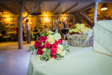 Centerpiece made of green leaves and fresh flowers stands on the dinner table. Wedding day. Fresh flowers decorations. Peach and awhite weddnig decorations.