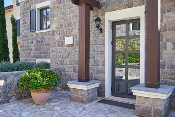 Entrance to the house with glass door and stone finished wall