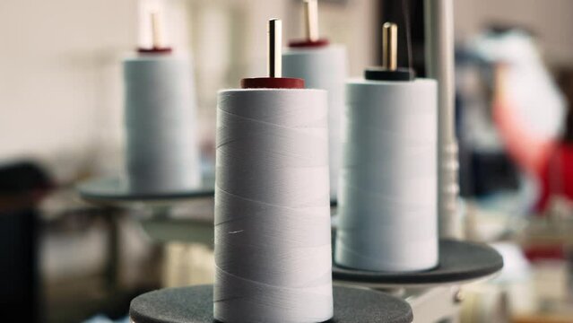 The thread is unwound from the spool while sewing by a seamstress on a sewing machine