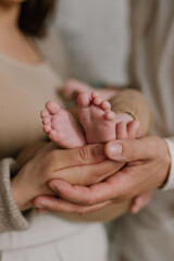 Mother and father holding their infant in minimalistic interior kissing small cute hand family 