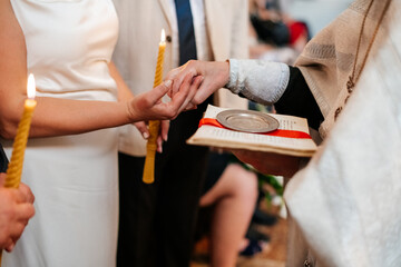 Obraz premium A couple holding hands during a wedding ceremony, with a priest in the background. A touching moment of commitment and love.