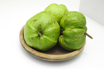 a group of fresh ripe Crystal guava (Psidium guajava) on a wooden plate isolated on white background