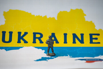 Metal figurine of a soldier on the background of the map of Ukraine.