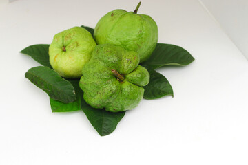 a group of fresh ripe Crystal guava (Psidium guajava) on green leaves isolated on white background.