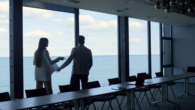 Business partners talking conflicting at panorama window. Angry man throw papers
