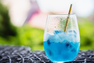 Glass of tasty blue cocktail and yellow lemons on blured background..Alcohol juicy fruit blue...
