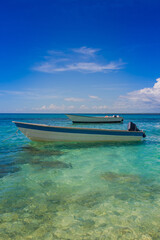 Fishing motorboats in beautiful turquoise water near the tropical exotic white beach in the Caribbean sea.