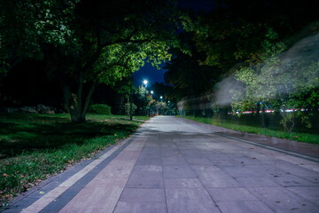 The teiled road in the night park with lanterns in autumn. Bench