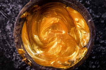 Golden ointment in a bowl on a gray marble background.