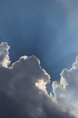 Fototapeta na wymiar Blue sky background with sun rays behind the clouds.
