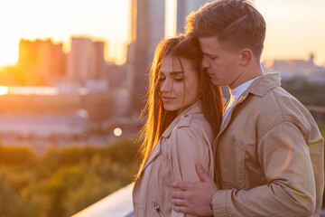 Beautiful happy young loving couple on a surprise date on a Saint Valentine's Day. Romantic date on the rooftop, summertime. Young man and beautiful girl. Newlyweds on honeymoon. Golden hour