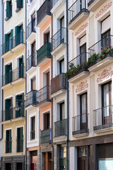 Fototapeta na wymiar facades of several restored old houses on a narrow street full of small balconies, historic downtown Pamplona, Navarra, Spain, vertical