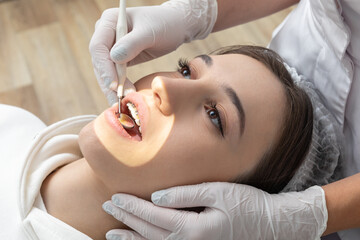 Young woman having dental check up in dental clinic. Dentist examining a patient teeth with dental...