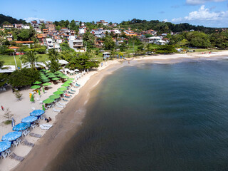 Fototapeta na wymiar Beautiful and peaceful beach with dark waters and colorful beach sunshade - Gamboa, Bahia, Brazil