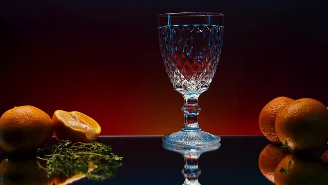 Close up of pouring orange soda into the glass. Stock clop. Soft drink with the taste of citrus and orange fruits on the reflective table surface.