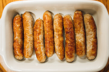 close up of browned, cooked individual breakfast sausage links in white dish