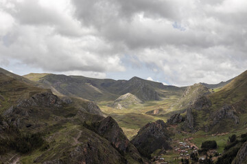 Obraz na płótnie Canvas HUANCAVELICA, PERU - JUNE 29, 2022: Beautiful panoramic view of some rocky mountains partially covered with vegetation. View of the sky with enough clouds that shaded the landscape.