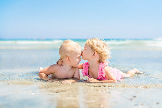 children's first kiss on beach at sea in ocean