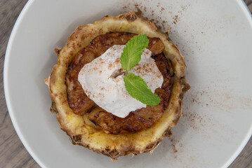 Overhead view of organic and natural scoop of ice cream served over baked cinnamon pineapple for a sweet dessert