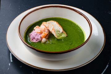 Broccoli, spinach cream soup with shrimp in a white bowl