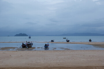 Fototapeta na wymiar Group of long- tail boats of fishermen inhabiting the west coast of Thailand, anchor and run ground on the beach to escape a storm. 