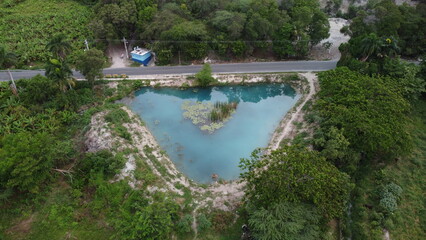 Fototapeta na wymiar Laguna en forma de diamante, con agua azul turqueza y una pequeña isleta en el centro, ademas de tener un bosque verde alrededor