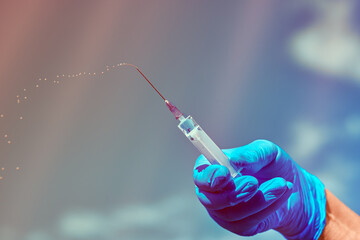 A syringe with medicine in his hands . A nurse with a dose of vaccine .