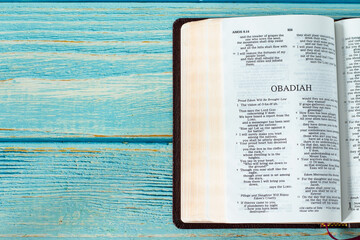 Obadiah open Holy Bible Book on a rustic wooden background with copy space. Top table view. Old...