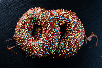 dark chocolate glazed donut with mixed colorful sprinkle