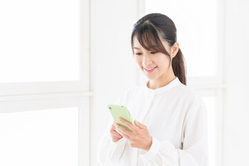 部屋でスマホを見る女性